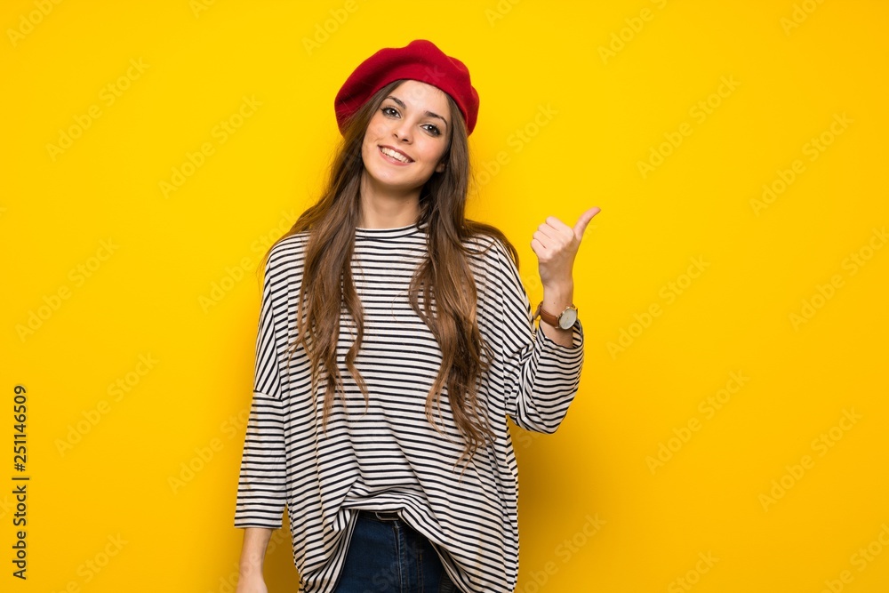 Girl with french style over yellow wall pointing to the side to present a product Girl with french style over yellow wall pointing to the side to present a product