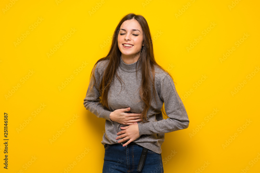 Young woman over yellow wall smiling a lot while putting hands on chest Young woman over yellow wall smiling a lot while putting hands on chest
