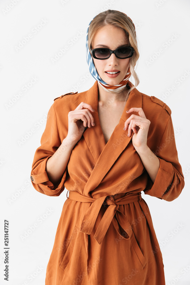 Beautiful young woman wearing silk stylish scarf posing isolated over white wall background wearing sunglasses.