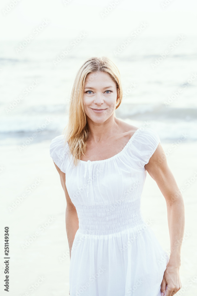 Attractive happy mature tourist blonde woman in long white dress on asian sand tropical beach. Attractive happy mature tourist blonde woman in long white dress on asian sand tropical beach.