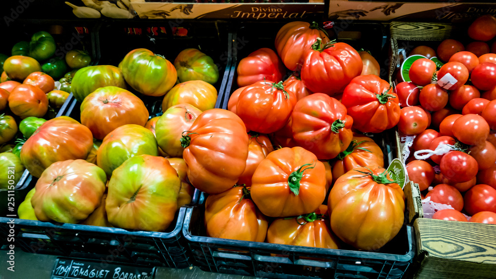 Fresh red, orange, purple and green tomatoes lie in boxes on the counter supermarket