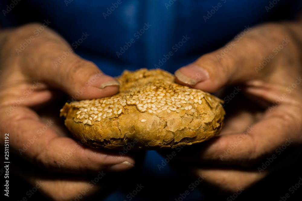 An old Chinese woman holds a Cheese sesame bread.