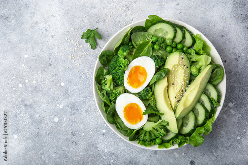 healthy green salad with avocado, eeg, broccoli, cucumber, green peas and spinach in white bowl