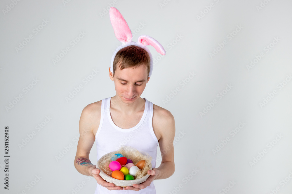Handsome guy with bunny ears holding basket with eggs. Happy Easter concept Handsome guy with bunny ears holding basket with eggs. Happy Easter concept