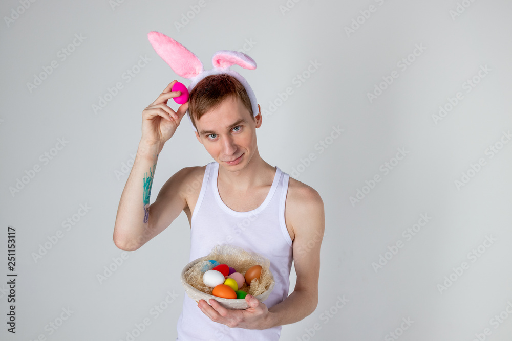 Handsome guy with bunny ears holding basket with eggs. Happy Easter concept Handsome guy with bunny ears holding basket with eggs. Happy Easter concept