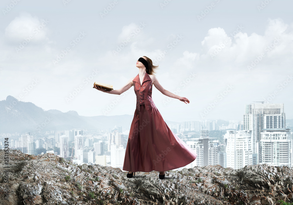 Girl against cloudy sky with opened book in palm as idea for knowledge Girl against cloudy sky with opened book in palm as idea for knowledge