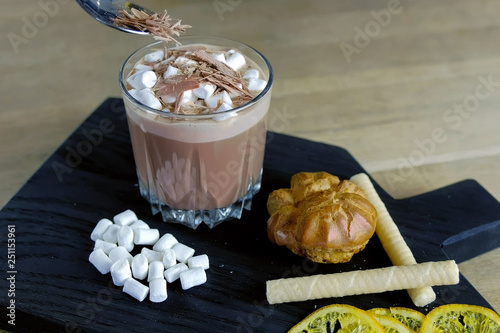 Barista sprinkles grated chocolate on cocoa with marshmallow in rock glass. Cooking Cocoa. Close-up view. photo