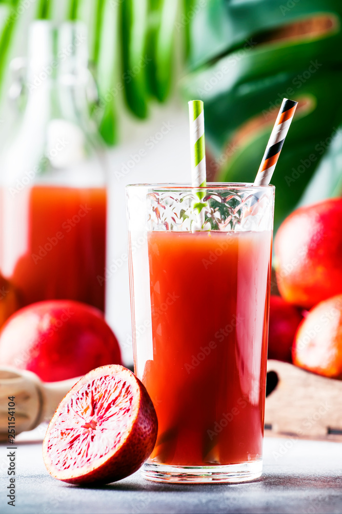 Summer juice or non-alcoholic refreshing healthy cocktail or drink from freshly squeezed red Sicilian orange, bright light table background. Selective focus Summer juice or non-alcoholic refreshing healthy cocktail or drink from freshly squeezed red Sicilian orange, bright light table background. Selective focus
