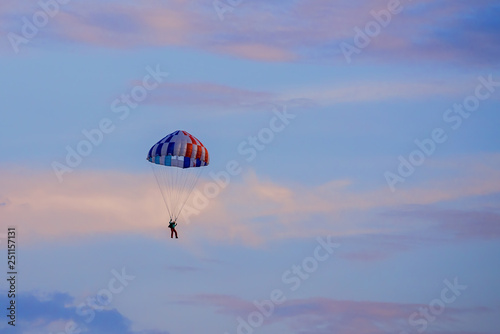 Parachutist falling from the sky in evening sunset dramatic sky. Recreational sport, Paratrooper silhouette on colored sky.