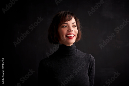 Studio portrait of cheerful young woman standing at dark background