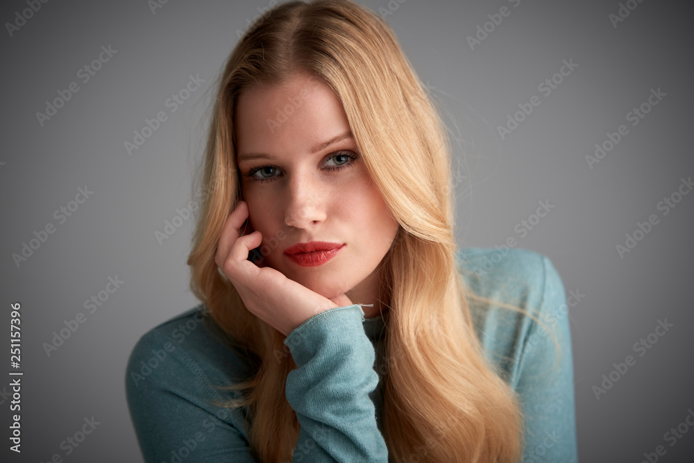 Portrait of blond hair young woman looking at camera and smiling while posing at light grey background Portrait of blond hair young woman looking at camera and smiling while posing at light grey background
