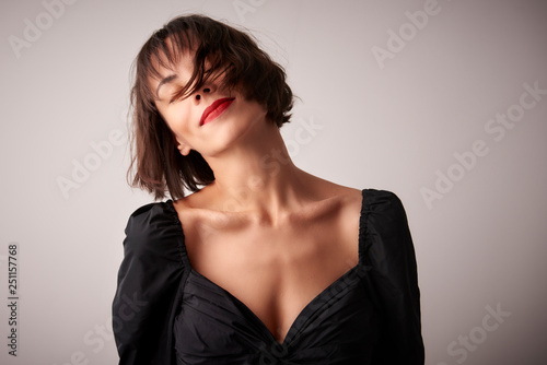 Close-up portrait of young woman with closed eyes daydreaming at light background
