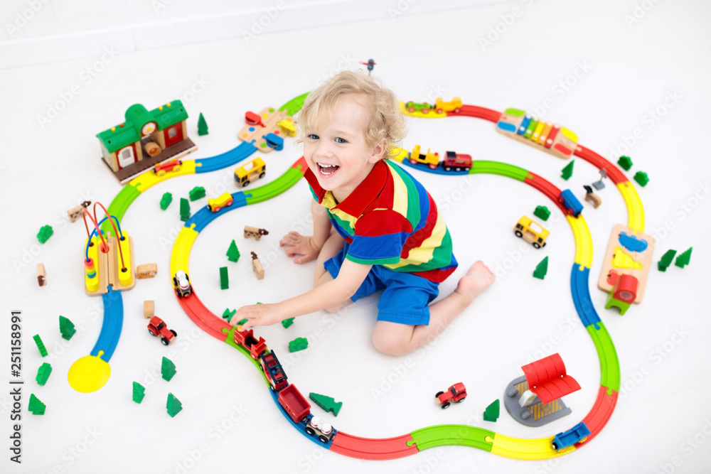 Obraz premium Child with toy train. Kids wooden railway.