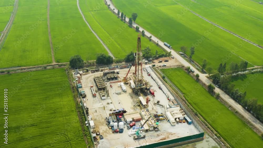 Oil and gas a land rig, onshore drilling rig, in the middle of a rice field aerial view from a drone Oil and gas a land rig, onshore drilling rig, in the middle of a rice field aerial view from a drone