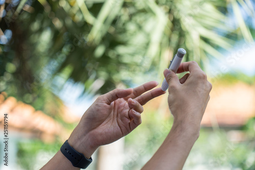 Close up of asian man's hands using lancet on finger to check blood sugar level by glucose meter, Healthcare medical and check up, diabetes, glycemia, and people concept