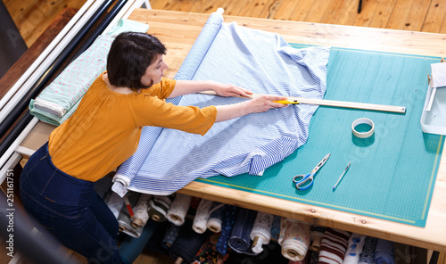 High angle view of female seller measuring textile