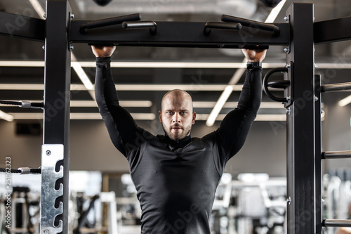Brutal athletic man dressed in black sorts clothes pulls up on the bar in the gym © Leika production