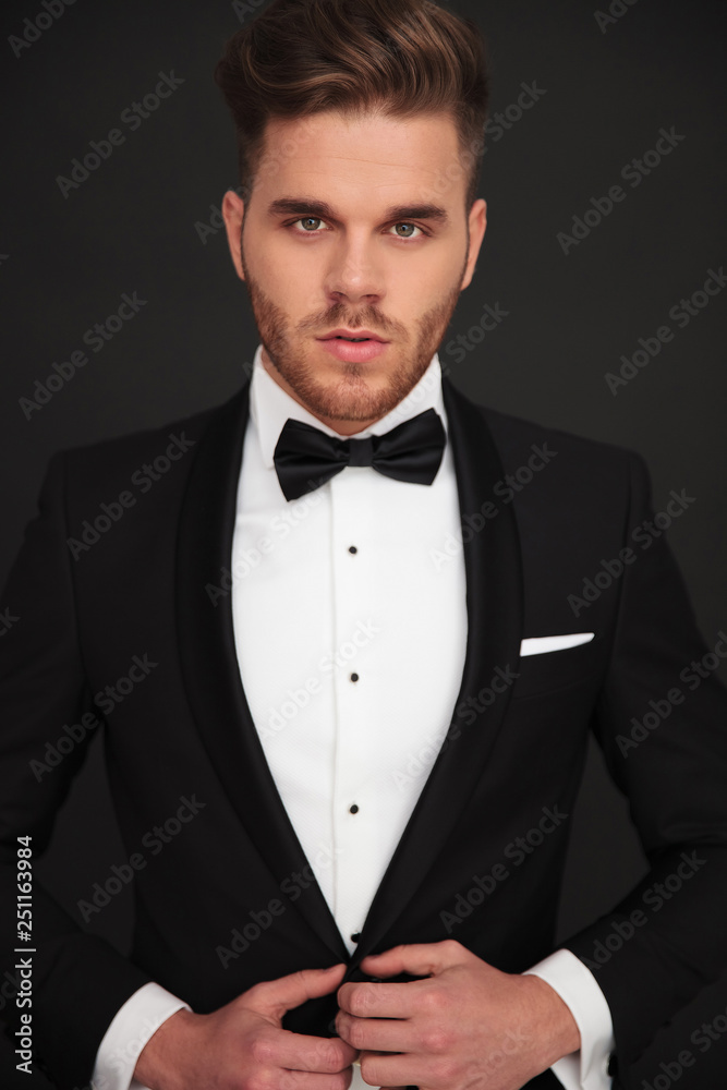 young groom looking into the camera and buttoning his coat young groom looking into the camera and buttoning his coat