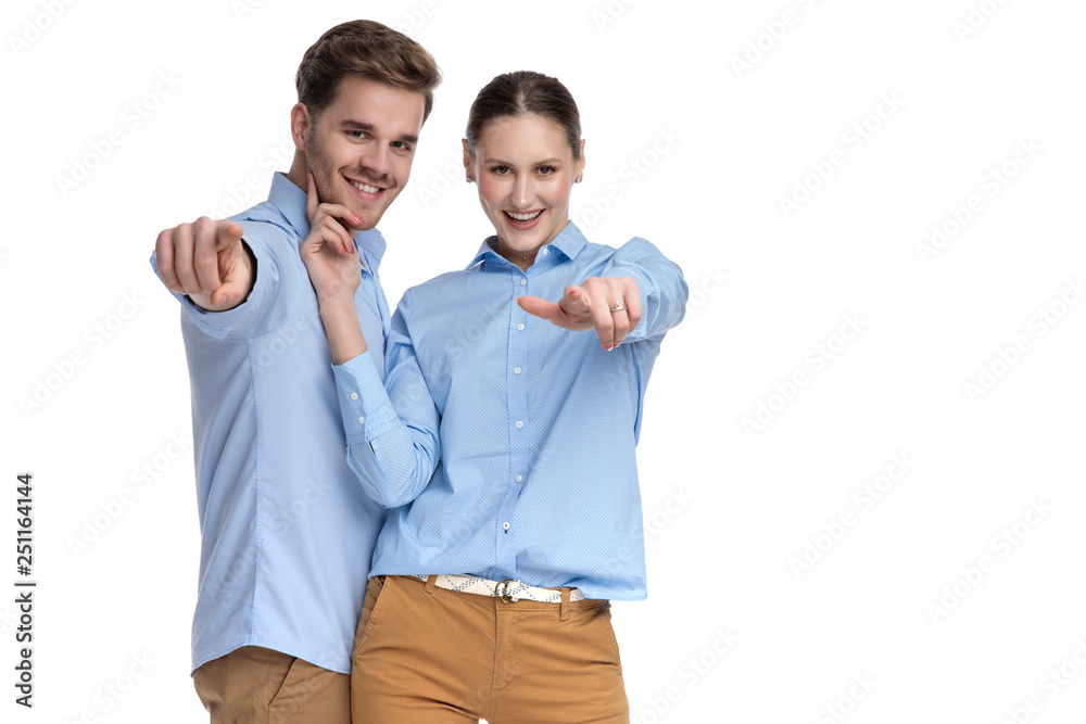 happy young casual couple pointing fingers together happy young casual couple pointing fingers together