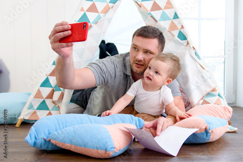 Father with baby boy taking selfie on mobile phone