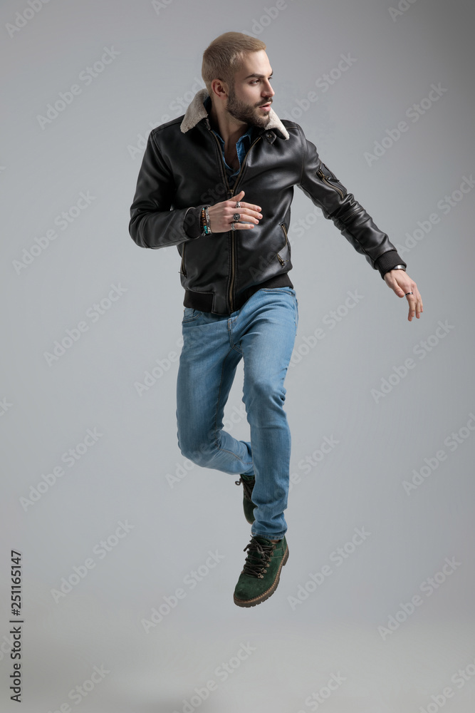 Fototapeta premium man in leather jacket and jeans jumps and looks away