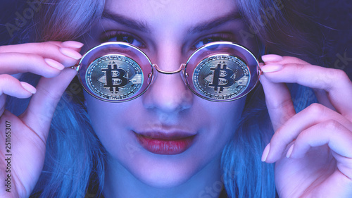 Portrait of a beautiful young blond woman with red lips in glasses with bitcoins close-up. Cryptocurrency concept. Creative neon lighting photo