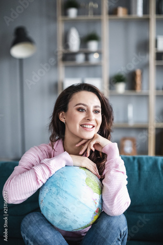Happy woman planning a trip or summer vacation with globe of the world laughing and smiling.