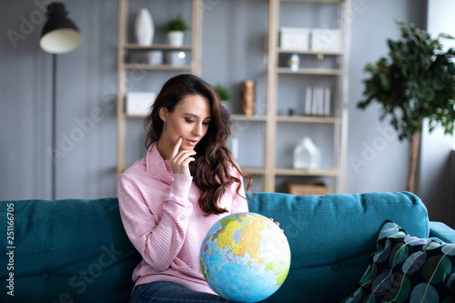 Woman is looking at a model of the globe sitting on a sofa.