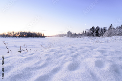 The ice lake and forest has covered with heavy snow and nice blue sky in winter season at Holiday Village Kuukiuru, Finland.