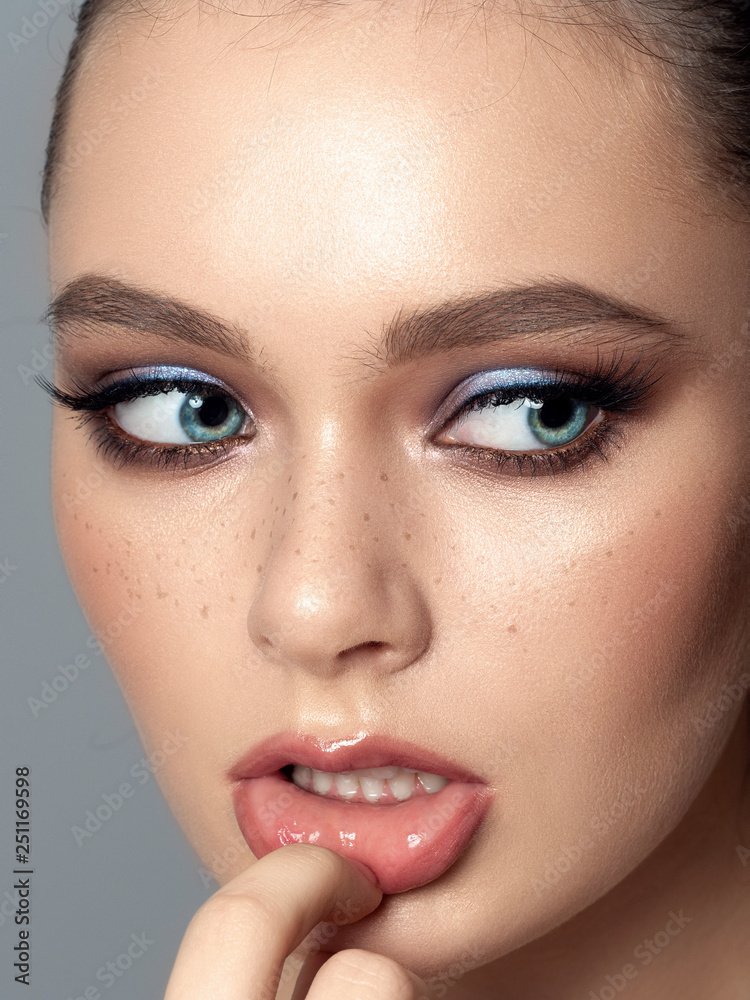 Portrait of young beautiful woman with freckles. Youth makeup concept. Studio shot Portrait of young beautiful woman with freckles. Youth makeup concept. Studio shot
