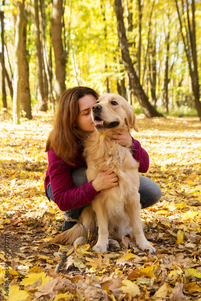 Beautiful woman with a golden retriever dog in autumn park