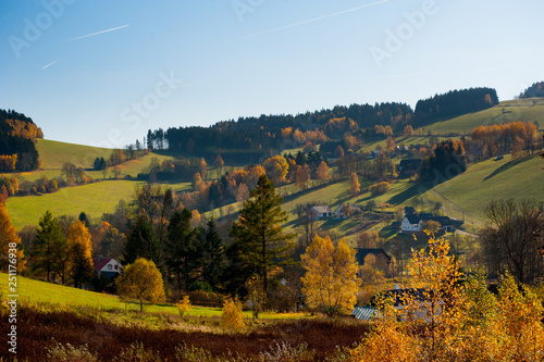 Beautiful summer landscape at sunset. Village. Lovely landscape of countryside hills and houses with blue sky and planes flying.