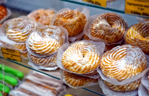 Rings with cottage cheese, sprinkled with powdered sugar, on the counter, in a pastry shop.