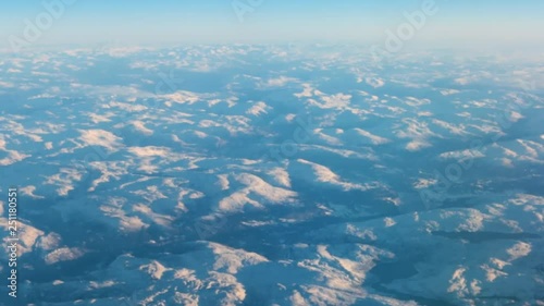 View from the porthole to the mountain peaks during the flight of the aircraft