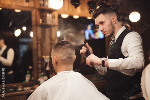 Professional barber splashes water on a head of client