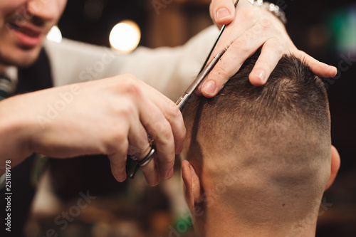 Professional haircut with scissor in a male barbershop salon