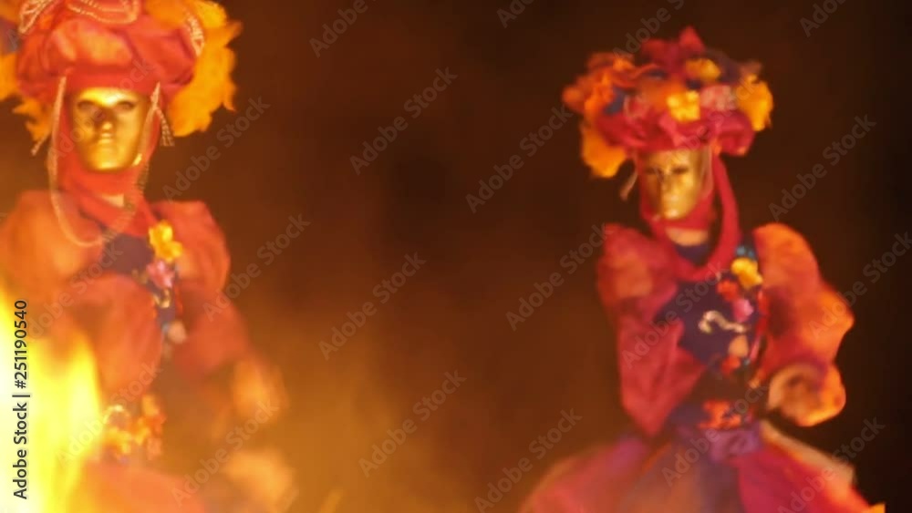bright dancers dance at night waving their hands in front of the fire in the foreground. bright dancers dance at night waving their hands in front of the fire in the foreground.