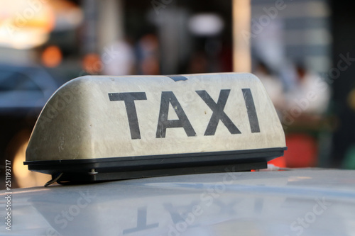 Taxi light sign or cab sign in drab white color and black text on the car roof.