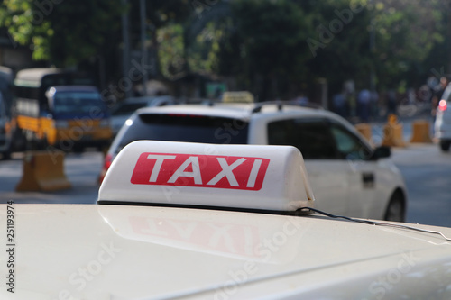 Taxi light sign or cab sign in white and red color with white text on the car roof.