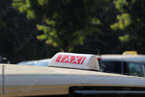 Taxi light sign or cab sign in white and red color with white text on the car roof.
