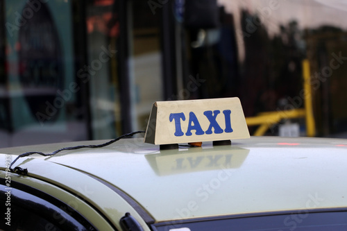 Taxi light sign or cab sign in drab white color with blue text on the car roof.