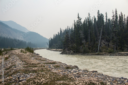 Smoke Obscured Mountains Rise Above Glacial Runoff in Alberta, Canada.