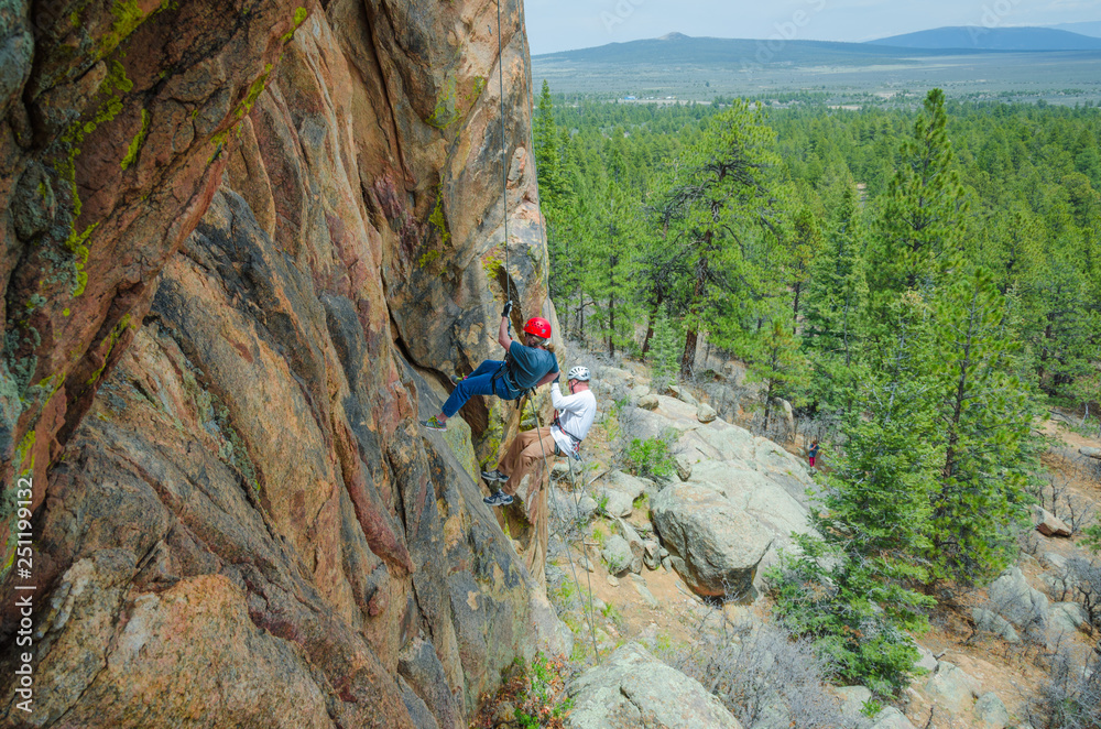 Woman and Man Rappel Down Colorful Granite Together Horizontal