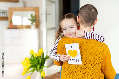 Happy Mother's Day or Birthday Background. Adorable young girl giving her mom, young cancer patient, homemade I LOVE MOM greeting card. Family celebration concept.