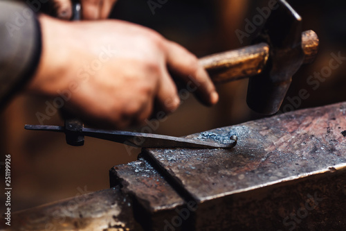 blacksmith makes an artistic forging of hot metal on the anvil.