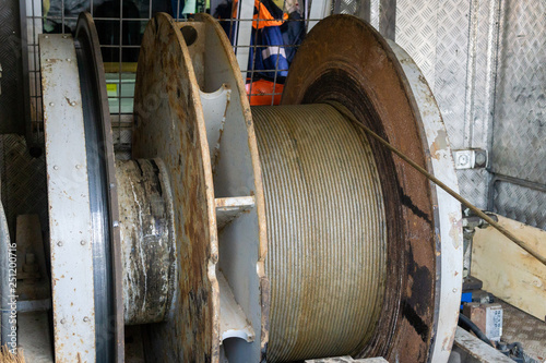 Wireline equipment hanging from top drive ready to be lowered downhole for logging. An oil well engineer works from the back of specialised van to log the condition of steel casing inside an oil well