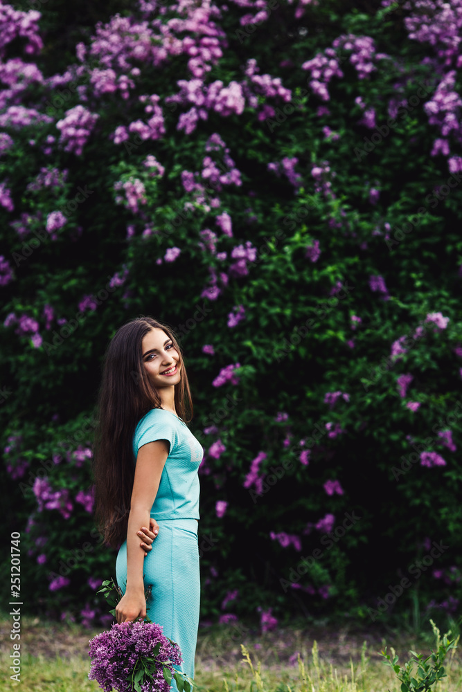 Wonderful spring. Cute young girl enjoys nature among the blossoming lilac and holds a bouquet. Wonderful spring. Cute young girl enjoys nature among the blossoming lilac and holds a bouquet.