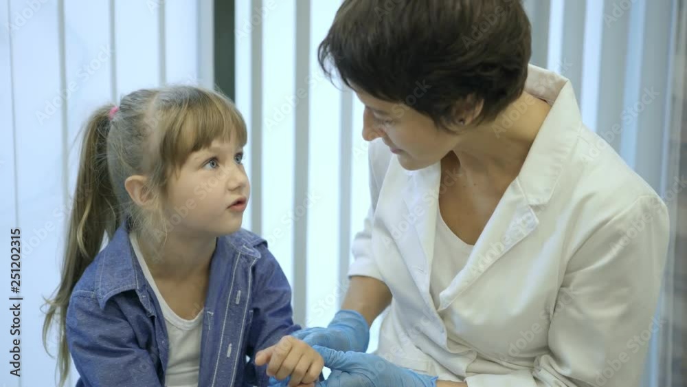 Sweet little girl talking to female pediatrician during medical examination in doctor office Sweet little girl talking to female pediatrician during medical examination in doctor office