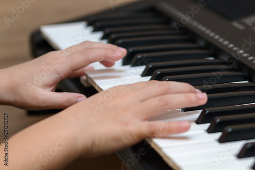 Hands of the child on the piano keys. Selective focus.