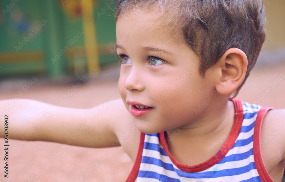 Funny cute happy boy playing on the playground. The emotion of happiness, fun, joy. Smile of a cute boy in striped t-shirt. Funny cute happy boy playing on the playground. The emotion of happiness, fun, joy. Smile of a cute boy in striped t-shirt.